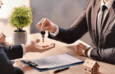 A person handing over keys to someone who has just signed a new tenancy contract. They have likely seen a rent increase.