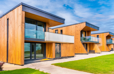 A row of modern, new-build, eco houses, with grass lawns in front. They are an example of sustainable property management.