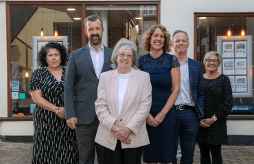 Six members of the team at Property Rentals stood smiling outside of their office.